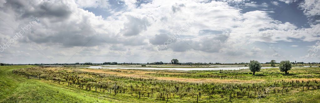 Panoramic view of the floodplains of the river IJssel at Vreugerijkerwaard nature reserve near Zwolle, the Netherlands, under a sky with dramatic clouds