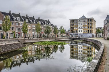 Helmond, Hollanda, 16 Ağustos 2019: Postmodern semtBrandevoort'ta neoclassist bir tarzda inşa edilen evler merkez meydandaki gölete yansıyor