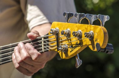 Lahey, Hollanda, 8 Temmuz 2019: Güneşli bir günde beş telli bas gitara dokunan parmaklar