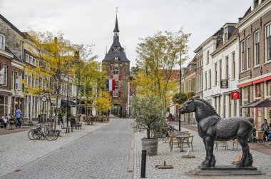 Vianen, Hollanda, 13 Ekim 2019: Voorstraat manzarası, eski şehrin ana caddesi, tarihi evler, kule ve kapılar, açık kafeler, bir at heykeli ve sonbahar ağaçları.