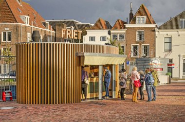 Middelburg, Hollanda, 9 Ekim 2019: oval zemin planı ve ahşap cepheli, arka planda geleneksel kanal evleri olan modern cips dükkanı