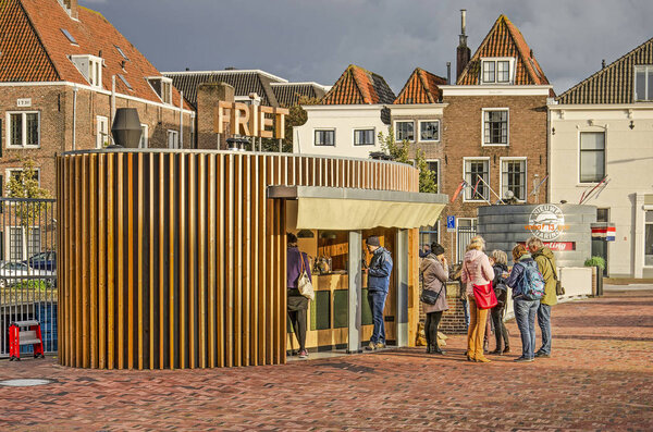Middelburg, The Netherlands, October 9, 2019: modern chip shop with oval floor plan and wooden facade, with traditional canal houses in the background