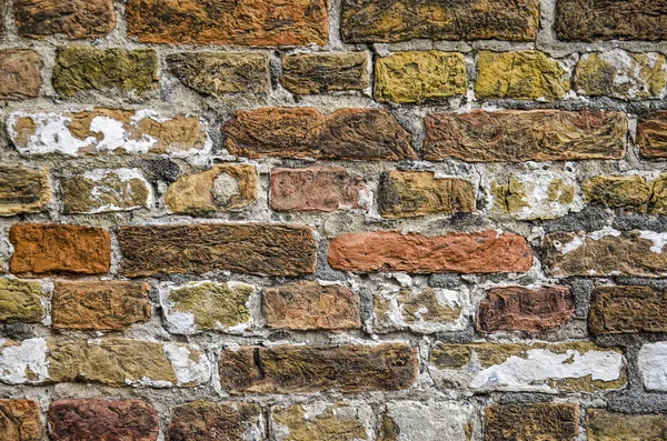 Close-up of a brick wall with colors in the range of yellow, red and brown as well as remnants of white plaster