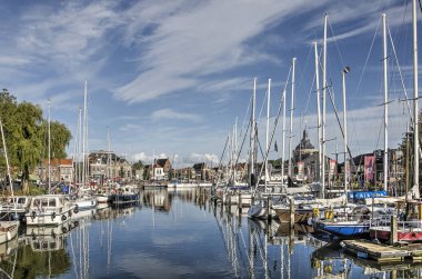 Enkhuizen, Hollanda, 13 Eylül 2019: Mavi gökyüzü, modern yatlar ve tarihi cepheler iç limanın ayna benzeri sularını yansıtıyor.