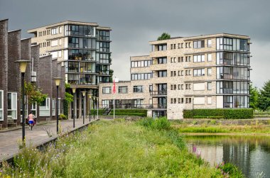 Zwolle, The Netherlands, August 2, 2020: recently built apartment buildings and quay houses facing lake Milligerplas clipart
