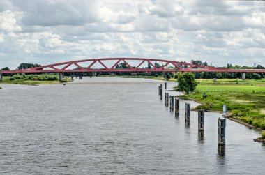 Zwolle, The Netherlands, July 21, 2020: view across the river IJssel towards the red arch of the Hanzeboog railway bridge clipart