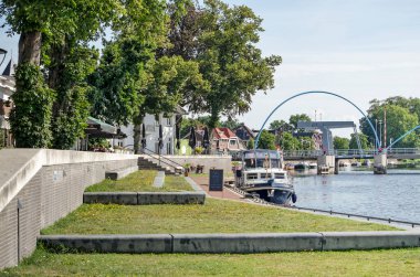 Dalfsen, Hollanda, 3 Ağustos 2020: Arka planda Vecht nehri üzerindeki köprü ile yenilenmiş rıhtımda çimenli yüzeyler