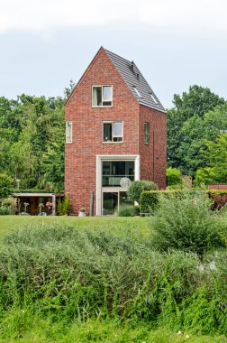 Zwolle, The Netherlands, July 27, 2020: luxury four storey house with a traditional shape and modern elements in a green environment clipart