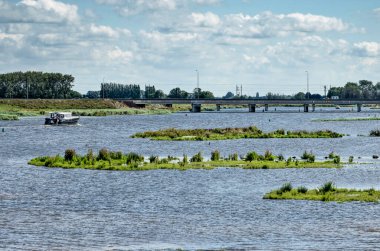 Kampen, Hollanda, 26 Temmuz 2020: Yeni Reevediep nehir kanalı boyunca küçük adaları, bir köprüsü ve küçük bir yatı olan