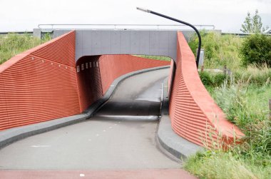 Berkel en Rodenrijs, Hollanda, 29 Ağustos 2020: yayalar ve kırmızı beton duvarlı ve eğri büğrü şekilli bisikletçiler için çapraz geçiş