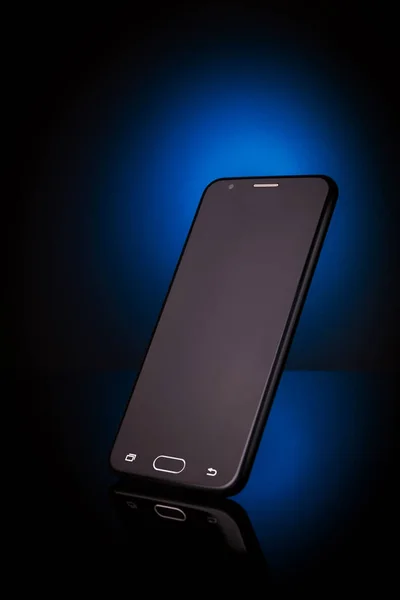 standing upright smartphone on reflective surface with blue light on background