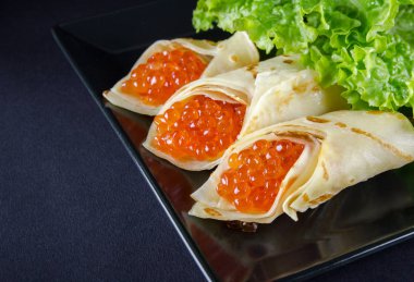 Kırmızı havyar ve salata ile doldurulmuş krep siyah plaka yatay fotoğraf bırakır 