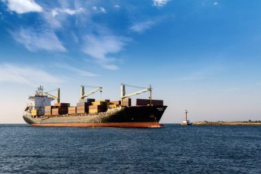 Limana girerken fenerden geçen konteyner gemisi. Gün ışığı, yaz fotoğrafı.