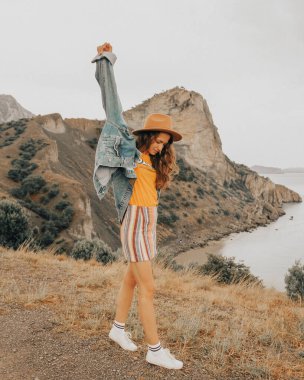 Dağlarda yaz tatilinde şapkalı güzel bir kız. Mavi gökyüzü ve deniz.