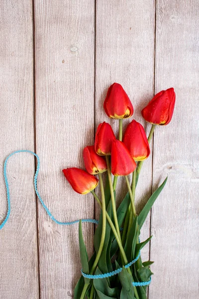 bouquet of red tulips. Red tulips with blue ribbon on a wooden background.