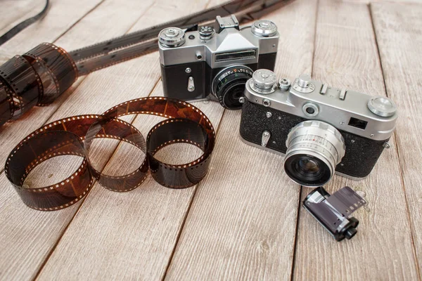 two retro cameras and a photographic film on a vintage wooden background