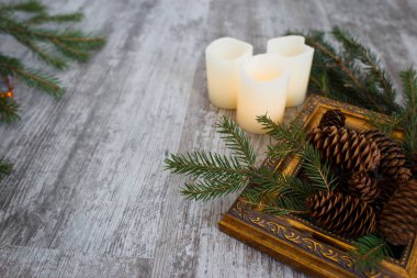 Çam dalları, Noel ışıkları, çam kozalakları yaldızlı çerçeve ve eski bir ahşap zemin üzerine mumlar ile Noel kompozisyon