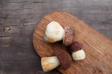 Üç çörek mantar yakın eski ahşap bir masa üzerinde bir ahşap kesme tahtası üzerinde yalan. Üstten görünüm