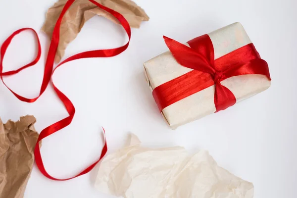 Gift wrapping process. Unsuccessful attempts to pack the box. Wrapped gift with ribbon and scraps of wrapping paper around on white background. Selective focus