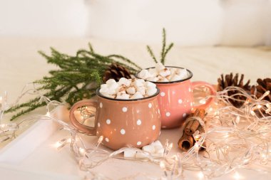 Kış tatil kompozisyon: iki şirin fincan kahve Noel ışıkları ve süslemeleri yakın çekim ile ahşap beyaz tepside marshmallow ile.