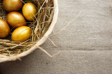 Altın yumurta saman, Sepet dokuma bir arka plan üzerinde en iyi görünümü kapatın. Paskalya kompozisyon. Kopya alanı