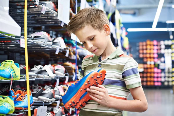 Garçon avec des bottes de football en magasin de sport — Photo