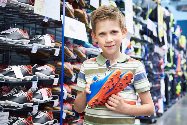 Хлопчик з футбольними черевиками в спортивному магазині — стокове фото