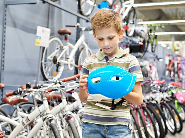 Jongen met sport helm voor fietsen in de winkel — Stockfoto