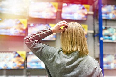 Buyer woman selects TV in store clipart