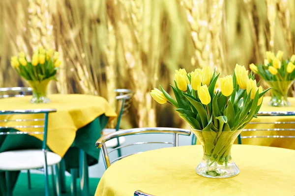 Yellow tulips on tables in interior — Stock Photo, Image