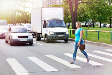 Woman crossing the street at a pedestrian crossing clipart