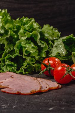 İtalyan bruschetta karanlık masada yemek pişirmek için malzemeler. Kiraz domates, peynir sos, salata yaprakları, sarımsak, zeytinyağı ve jambon ile İtalyan bruschetta