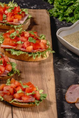 Doğranmış domates, salata yaprakları, jambon ve ızgara ekmek sosu ile İtalyan ev yapımı bruschetta. Yatay görünüm