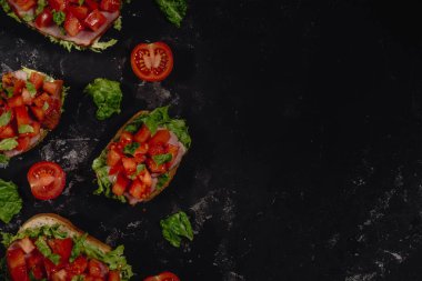 Doğranmış domates, mozzarella sos, salata yaprakları ve karanlık baton arka plan üzerinde jambon ile geleneksel İtalyan Bruschetta. Geleneksel İtalyan meze veya aperatif, meze. Ana sayfa görünümü ile kopya alanı, co