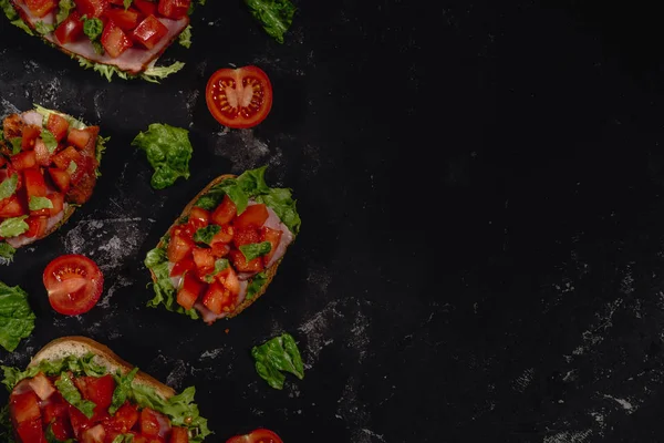 Doğranmış domates, mozzarella sos, salata yaprakları ve karanlık baton arka plan üzerinde jambon ile geleneksel İtalyan Bruschetta. Geleneksel İtalyan meze veya aperatif, meze. Ana sayfa görünümü ile kopya alanı, co