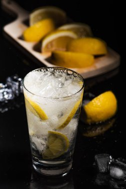 Cin-tonik limon dilimleri ve Ice cube, sırtında siyah arka plan üzerine limon ve buz ile süsleyin