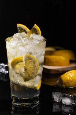 Köpüklü su veya diğer şeffaf içki ve bir dilim limon ve buz küpleri siyah arka plan yatay görünümünde güzel cam