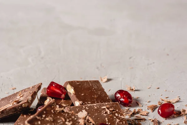 Broken chocolate pieces and chocolate powder, chocolate with hazelnut, chocolate and red pomegranate on beton background with copy paste place