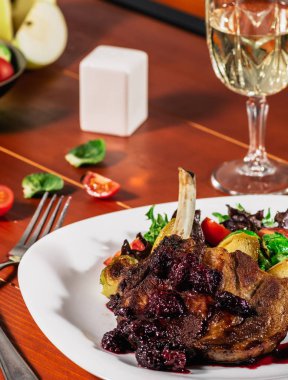 Kavrulmuş et kızartma apple ile brussel filizlenir, kiraz domates ve salata yaprakları beyaz bir tabak ve ahşap arka plan üzerinde beyaz şarap