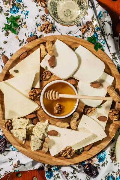 Tasting cheese dish with herbs and snacks on old light wooden table. Food for wine and romantic, cheese delicatessen. Menu design horizontal. Top view. — Stock Photo, Image