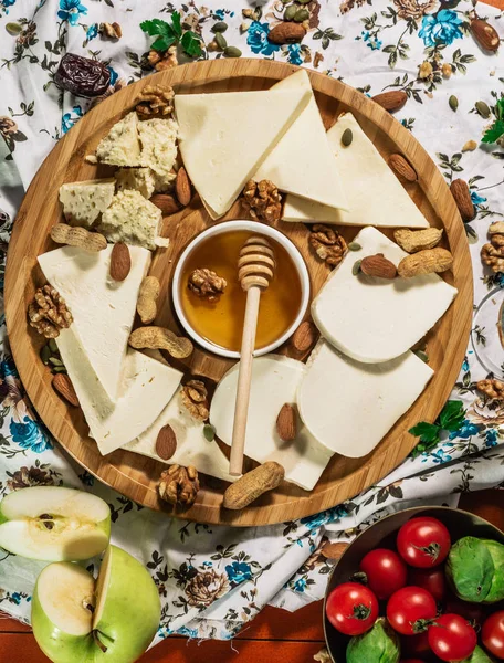 Tasting cheese dish with herbs and snacks on old light wooden table. Food for wine and romantic, cheese delicatessen. Menu design horizontal. Top view. — Stock Photo, Image