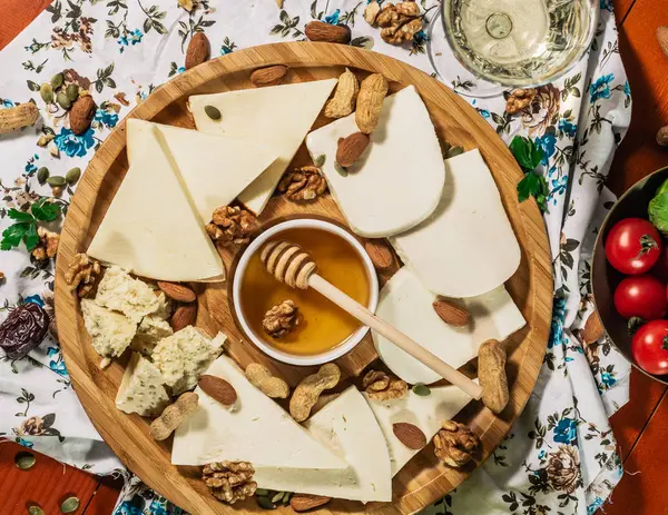 Tasting cheese dish with herbs and snacks on old light wooden table. Food for wine and romantic, cheese delicatessen. Menu design horizontal. Top view. — Stock Photo, Image