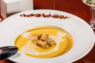 Ahşap arka plan üzerinde beyaz plaka kruton bir krem ile baharatlı kabak veya mercimek çorbası