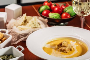 Kavrulmuş kabak ve havuç çorbası Krem, balkabağı tohumları ile. Kruton, peynir ve ahşap arka plan üzerinde beyaz şarap ile devam eder. Kopya alanı