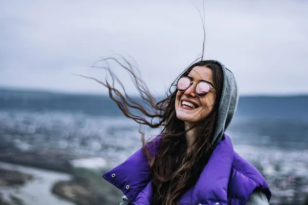 tender beautiful brunette girl with sunglasses in a purple coat in the spring, cold weather, the theme of beautiful people and fashion