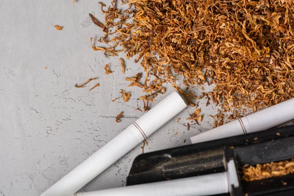 Folhas de tabaco cortadas e secas. Um dispositivo para fazer cigarros em casa. Cigarro de tabaco caseiro, espaço em pasta de cópia, no fundo cinza — Fotografia de Stock