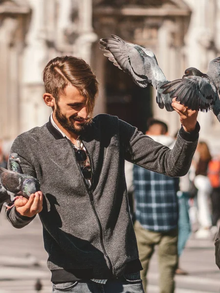 Happy Young man posing with pigeons in the milanese street with ancient church Duomo di Milano on background. Cute happy 23 years old man posing in Milan, Italy. — Stock Photo, Image