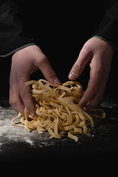 Chef hands making spaghetti, pasta, noodles with fresh pasta on black table with. — Stock Photo, Image