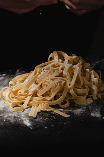 Chef hands making spaghetti, pasta, noodles with fresh pasta on black table with. — Stock Photo, Image