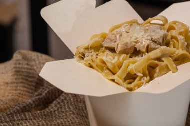 Ev yapımı Makarna, Erişte, fettuccine Alfredo veya Bolognese ahşap bir arka plan üzerinde beyaz bir kutu içinde uzak almak için yakın çekim. logo veya kopyala yapıştır metni için yer